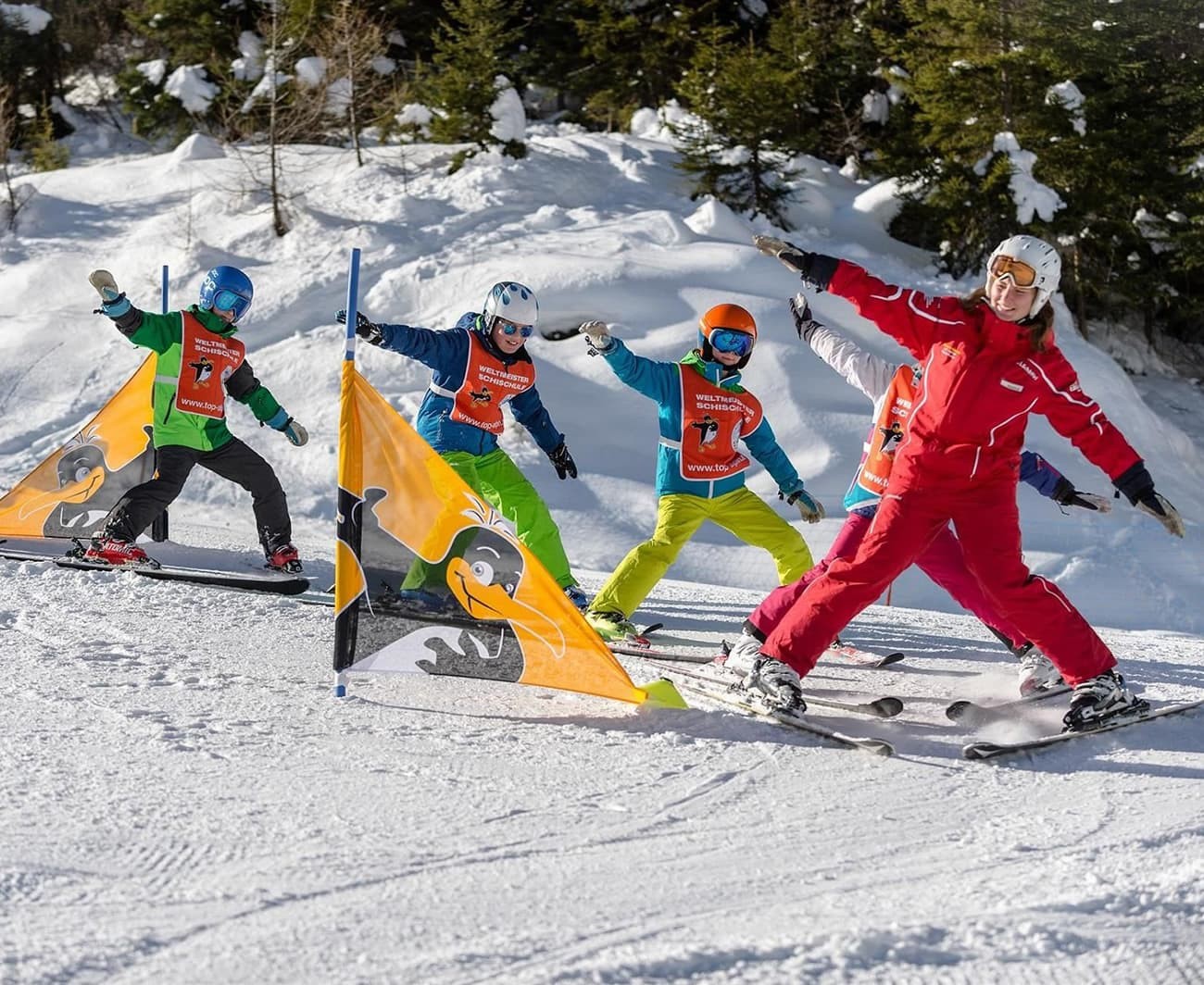 Ski instructor leads children through colorful ski gates on a snowy slope