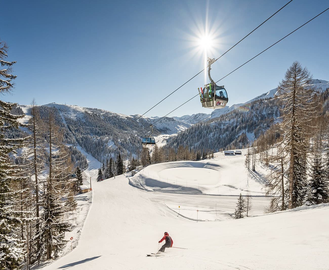 Skier in snowy landscape beneath bright sun and ski lift