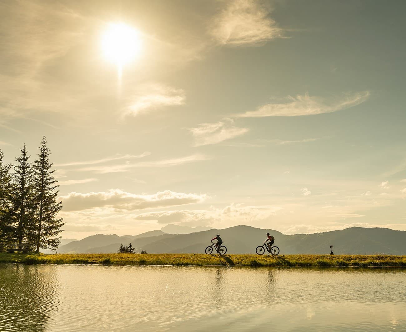 Zwei Radfahrer fahren bei Sonnenuntergang entlang des Seekarsees am Gamskogel