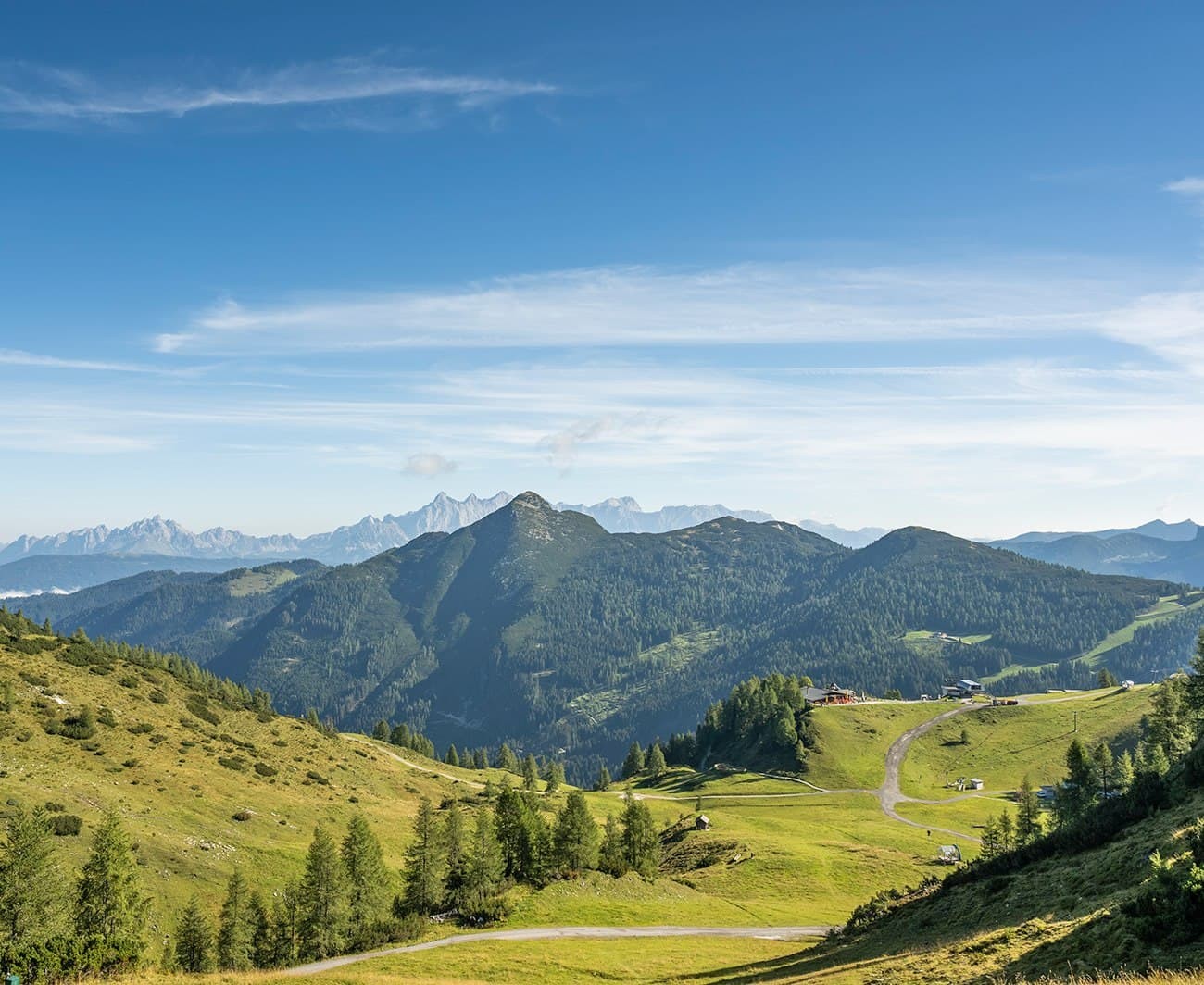 A scenic view of rolling green hills and distant mountains under a clear blue sky