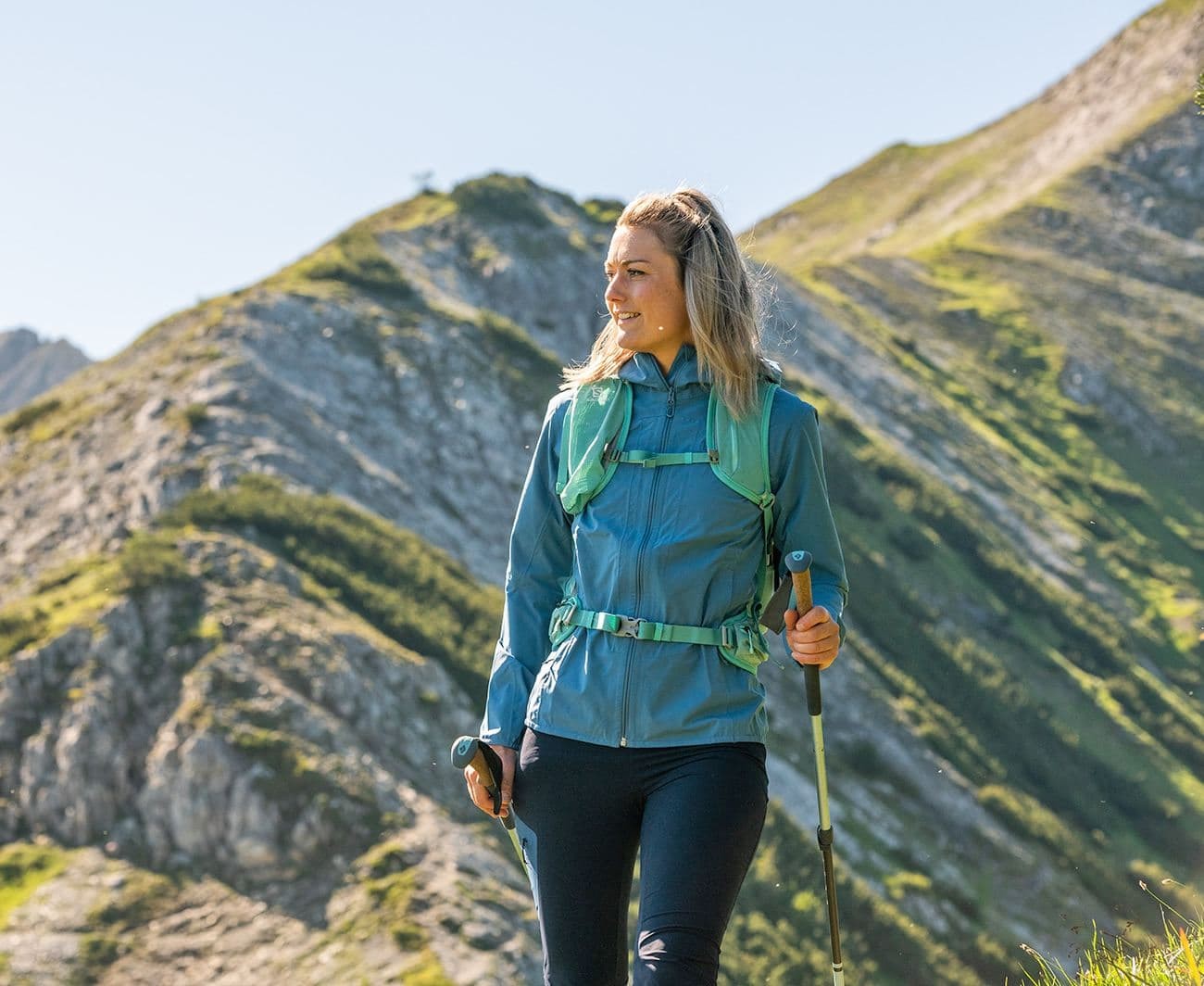 Woman hiking with trekking poles in mountainous landscape