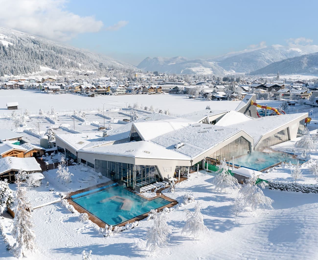Snow-covered buildings of the Therme Amadé and pools in a picturesque winter landscape